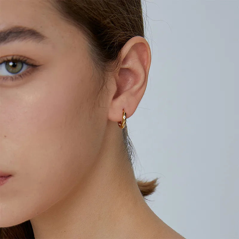 Boucles d’oreilles créoles dorées pour femme en plaqué or, au design facetté angulaire incrusté de strass brillants. Bijou moderne et graphique au style chic et minimaliste, léger et lumineux, parfait pour un look structuré et élégant