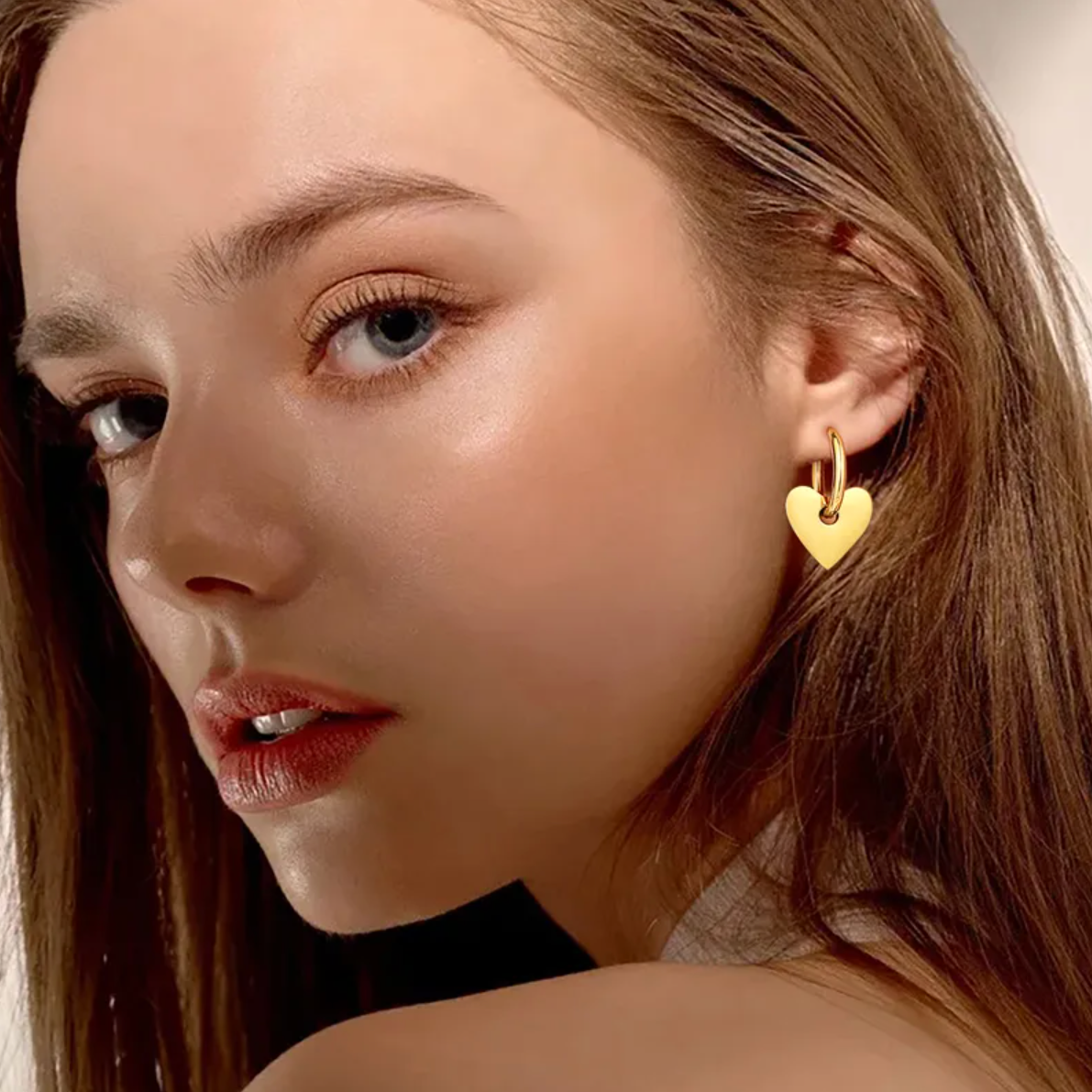 Boucles d’oreilles créoles dorées pendantes pour femme en acier inoxydable, ornées d’un pendentif cœur poli brillant. Bijou romantique et moderne, hypoallergénique et résistant à l’eau, parfait pour un look féminin chic et intemporel au quotidien