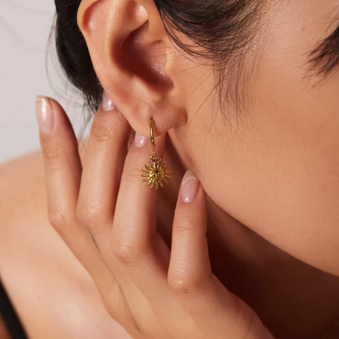 Boucles d’oreilles créoles dorées en acier inoxydable avec pendentif soleil rayonnant, bijou bohème chic symbolisant la lumière et la vitalité. Résistantes à l’eau et hypoallergéniques, parfaites pour un style solaire et féminin