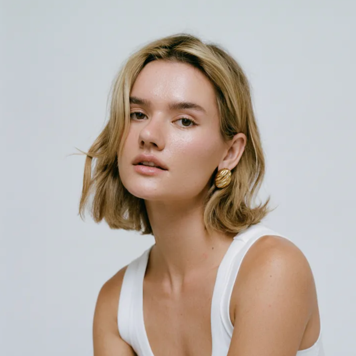 Boucles d’oreilles dorées en acier inoxydable, forme ovale ondulée façon coquillage sculpté, finition miroir brillante. Bijou chic et moderne pour femme, résistant à l’eau et hypoallergénique