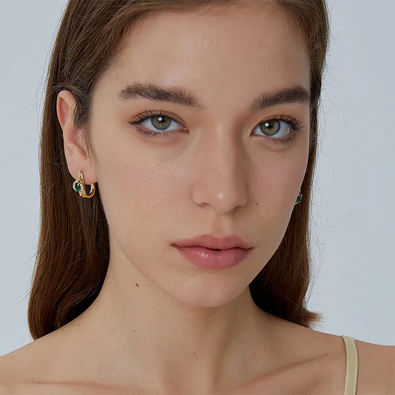 Boucles d’oreilles dorées pour femme en plaqué or, ornées d’une pierre ovale verte effet émeraude entourée de zircons scintillants. Bijou élégant et raffiné au design galbé, confortable et sophistiqué, parfait pour une tenue chic ou de soirée