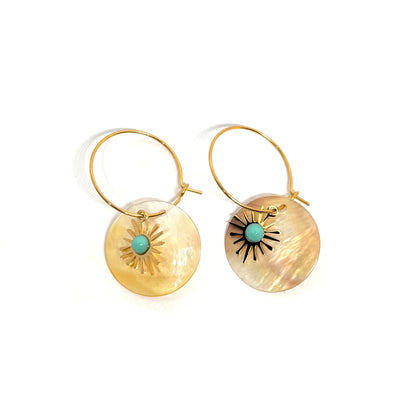 Boucles d’oreilles pendantes dorées en acier inoxydable, disque en nacre naturelle décoré d’un motif soleil et d’un centre turquoise. Bijou bohème chic et lumineux, hypoallergénique et résistant à l’eau