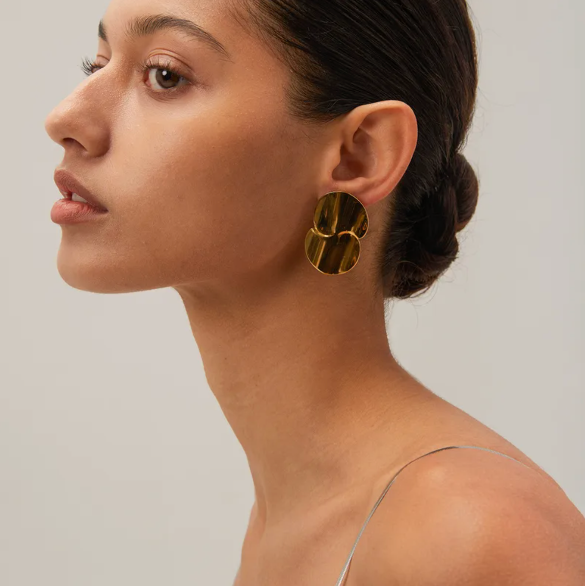 Boucles d’oreilles puces dorées pour femme en acier inoxydable, au design organique et sculptural inspiré de pétales fusionnés. Bijou arty et moderne au fini miroir, résistant à l’eau et hypoallergénique, idéal pour un look élégant ou de cérémonie