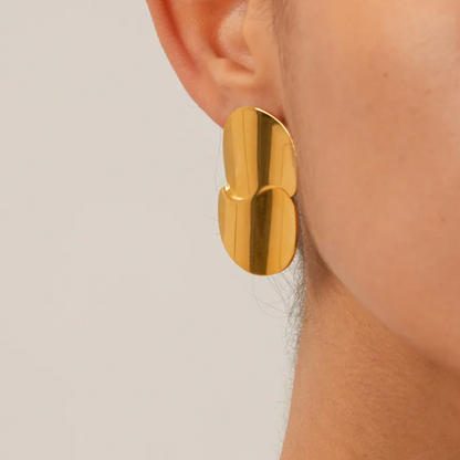 Boucles d’oreilles puces dorées pour femme en acier inoxydable, au design organique et sculptural inspiré de pétales fusionnés. Bijou arty et moderne au fini miroir, résistant à l’eau et hypoallergénique, idéal pour un look élégant ou de cérémonie