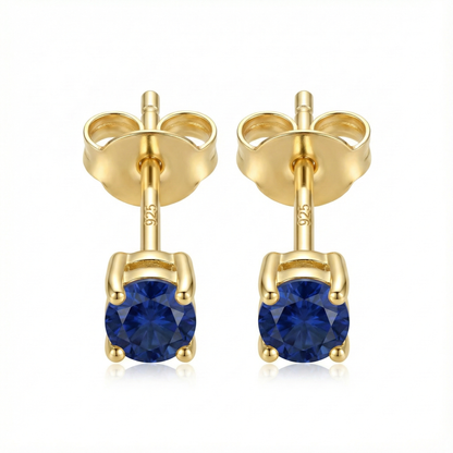 Boucles d'oreilles puces en argent doré avec pierre zircon couleur saphir bleu roi, style joaillerie élégant.