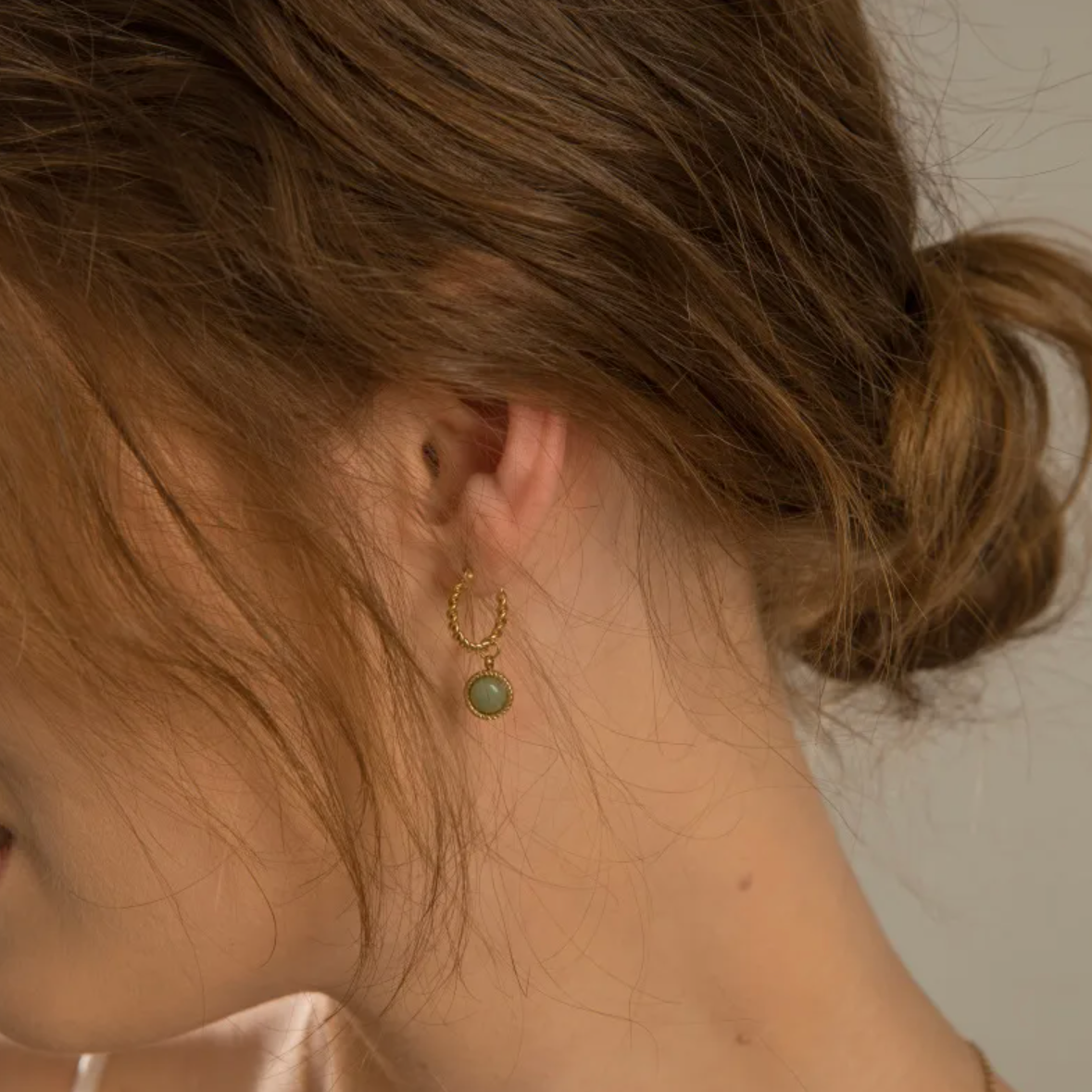Des créoles élégantes au style vintage revisité, associant une structure torsadée en acier inoxydable doré 18K à une pierre naturelle verte à l’éclat doux et énigmatique. Un design à la fois raffiné et texturé, pensé pour capter la lumière et souligner la forme du visage.

Matériau : Acier inoxydable couleur doré, finition PVD 18K, hypoallergénique et résistant à l’eau. Pierre naturelle verte en cabochon lisse (visuel exact : photo secondaire).

Dimensions : 15 mm (diamètre extérieur) x 8 mm (cabochon). Poi