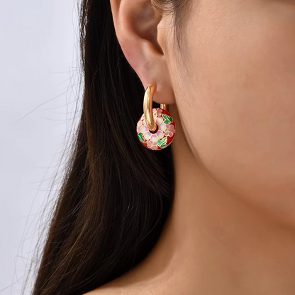 Boucles d’oreilles créoles couleur or avec pendentif rond émaillé motif floral multicolore.