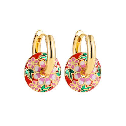Boucles d’oreilles créoles couleur or avec pendentif rond émaillé motif floral multicolore.