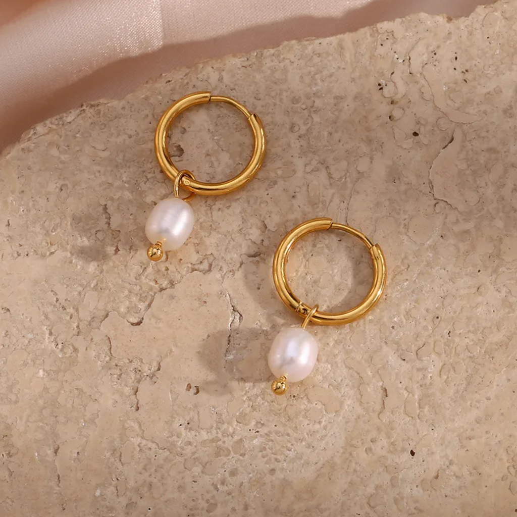 Des créoles pendantes en acier inoxydable doré, rehaussées de perles blanches en goutte, pour une allure à la fois minimaliste, chic et féminine. L’équilibre parfait entre modernité et douceur intemporelle.

Type : Boucles d’oreilles pendantes – créoles.
Matériau : Acier inoxydable couleur doré, perles synthétiques blanches, hypoallergénique, résistant à l’eau et à l’oxydation.

Dimensions : Longueur totale 2,9 cm, perle 1,6 cm, poids 4 g la paire.

Design : Anneaux ronds dorés d’où pend une perle blanche o