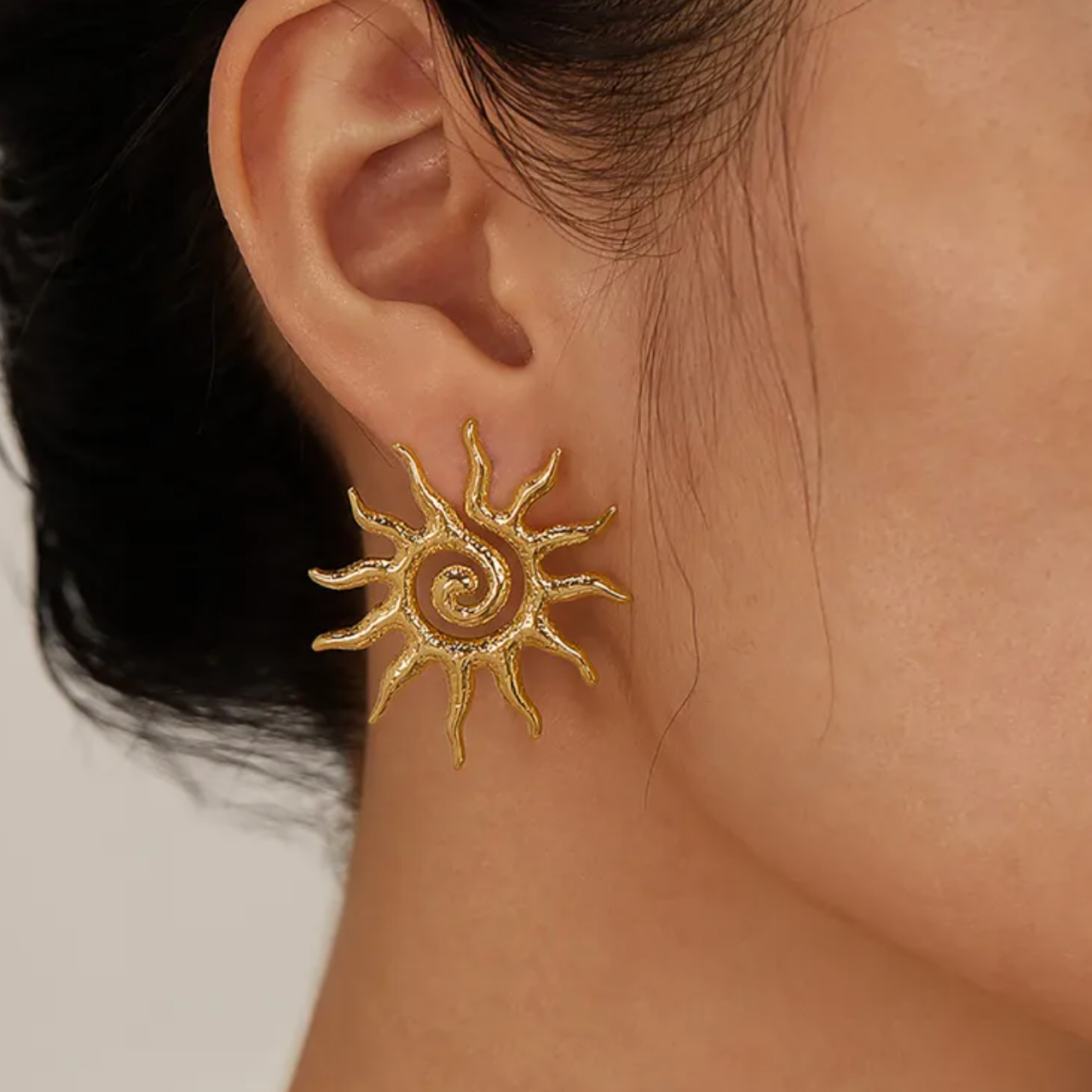 Ces boucles d’oreilles clous en forme de soleil stylisé affichent une spirale centrale éclatante, évoquant la chaleur et l’énergie vitale. Leur design texturé apporte du caractère et une touche solaire à votre look.

Matériaux : Acier inoxydable couleur dorée – résistant à l’eau, hypoallergénique, finition brillante.

Dimensions : Diamètre ≈ 2,8 cm – Type : clous d’oreilles – Fermoir sécurisé à poussette.

Style : Une paire de boucles audacieuses et solaires, à porter seule pour un effet rayonnant ou en acc