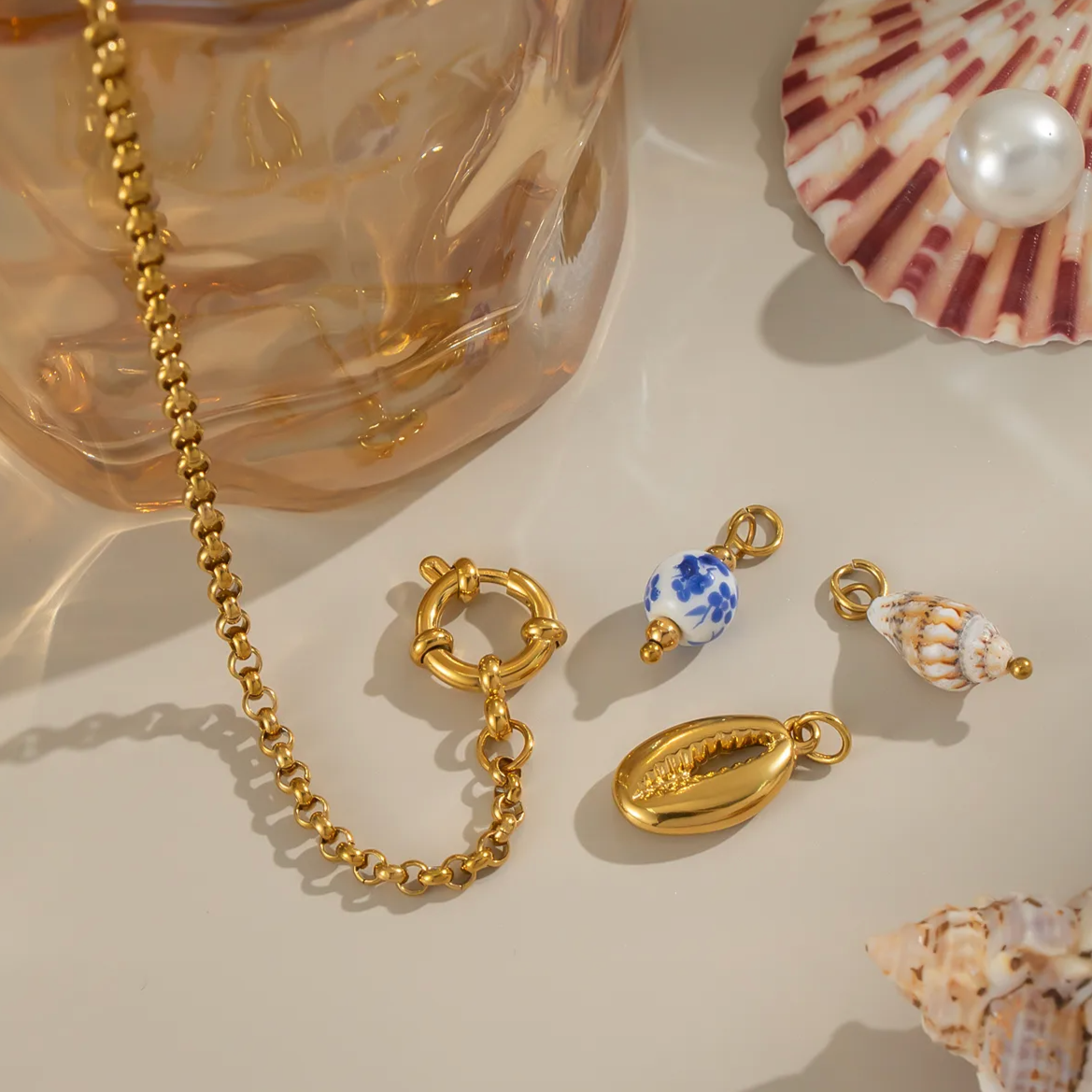 Un bracelet doré tendance, agrémenté de trois charms délicats : un cauri doré, une perle céramique bleu et blanc, et un petit coquillage naturel. Une pièce solaire et estivale, parfaite pour les tenues de bord de mer ou les looks bohèmes.

Matériau : Acier inoxydable couleur doré, hypoallergénique et résistant à l’eau. Éléments en céramique et résine.

Dimensions : Longueur 19 cm – taille des charms jusqu’à 1,8 cm – poids total 7,3 g.

Design : Maillons fins dorés à effet torsadé, fermoir anneau à bascule. 