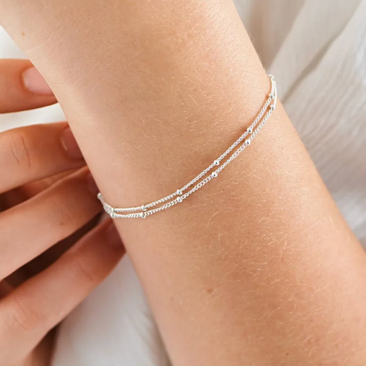 Bracelet femme en acier inoxydable couleur argent, composé de deux chaînes perlées entrelacées. Bijou fin, élégant et durable, résistant à l’eau, hypoallergénique et ajustable, parfait pour un look minimaliste chic au quotidien.