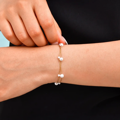 Bracelet femme double rang en acier inoxydable couleur or, orné de perles blanches de tailles variées. Bijou élégant et minimaliste, ajustable, léger et raffiné, parfait pour un look féminin et sophistiqué au quotidien ou en soirée