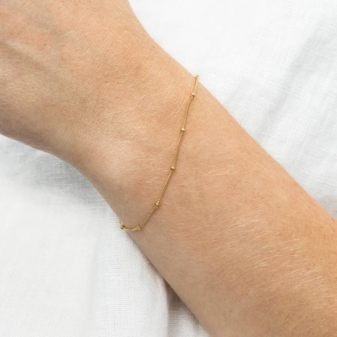 Bracelet délicat à maille fine perlée, en couleur doré 14K, conçu pour se poser en toute discrétion sur le poignet. Minimaliste mais travaillé, il capte subtilement la lumière grâce à ses petites perles d’espacement intégrées à la chaîne.

Matériaux : Acier inoxydable couleur doré 14K – résistant à l’eau, sans ternissure, hypoallergénique.

Dimensions : 15 cm + 3 cm d’extension – taille ajustable.

Design : Chaîne ultra fine, ponctuée de mini perles fixes régulières. Fermoir mousqueton discret.

Style : Par