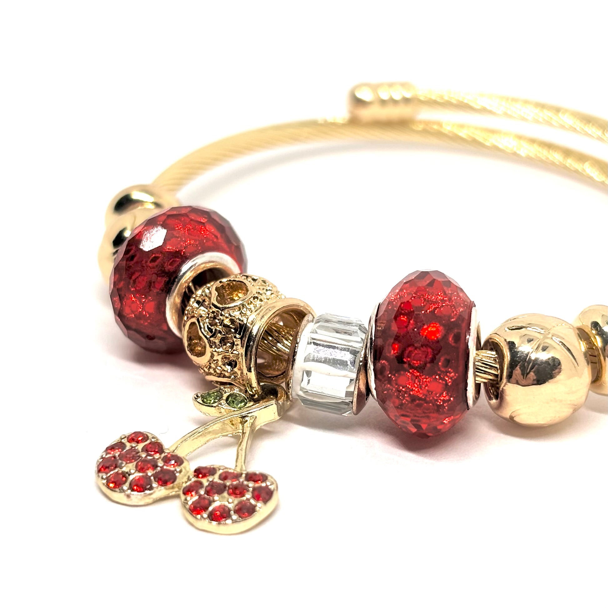 Bracelet rigide femme en acier inoxydable doré, décoré de charms scintillants dont une cerise rouge en zircon cubique et perles de cristal. Bijou fantaisie original et chic, au design coloré, audacieux et lumineux, parfait pour un look fruité et tendance