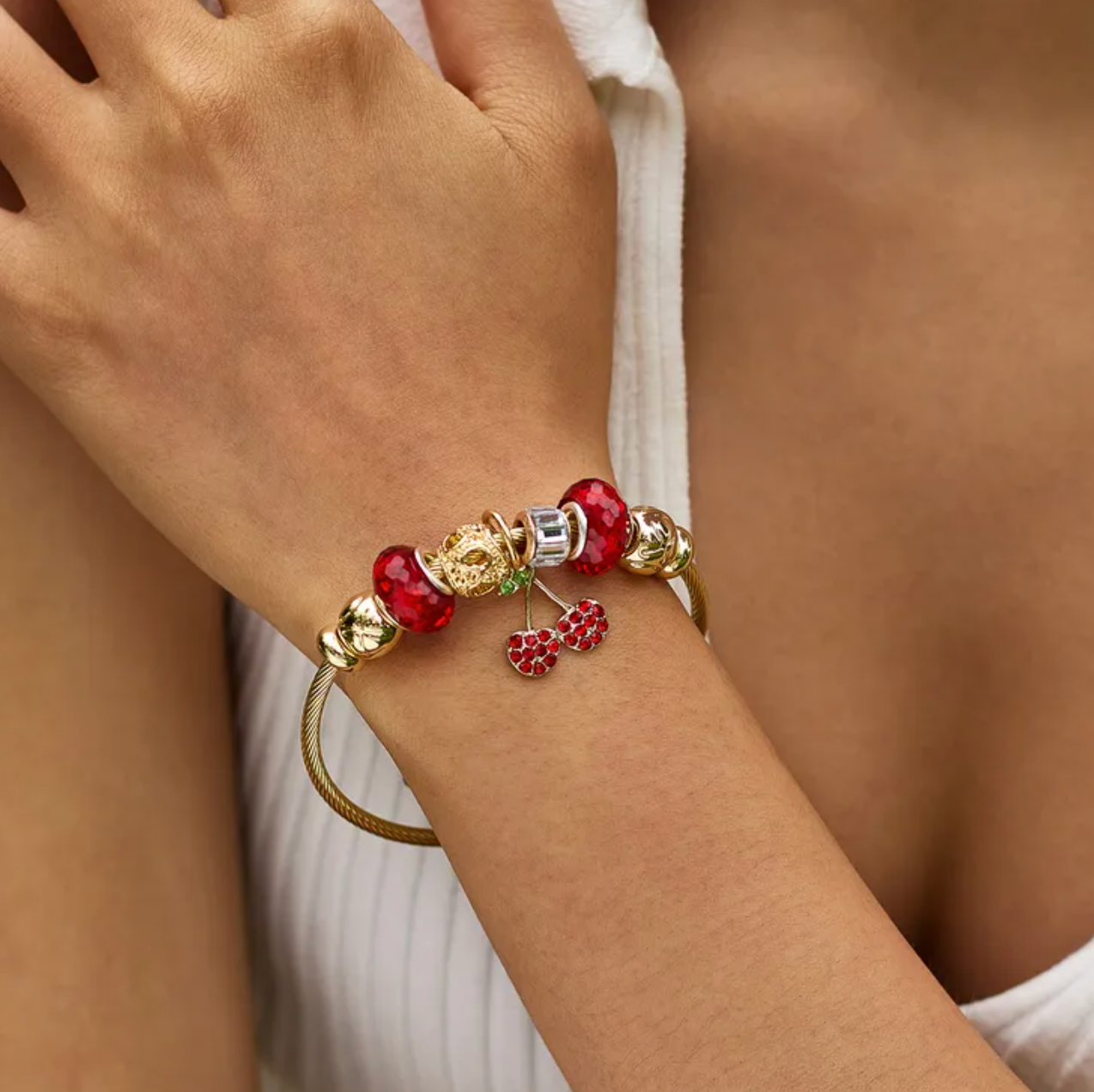 Bracelet rigide femme en acier inoxydable doré, décoré de charms scintillants dont une cerise rouge en zircon cubique et perles de cristal. Bijou fantaisie original et chic, au design coloré, audacieux et lumineux, parfait pour un look fruité et tendance