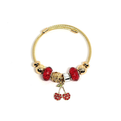 Bracelet rigide femme en acier inoxydable doré, décoré de charms scintillants dont une cerise rouge en zircon cubique et perles de cristal. Bijou fantaisie original et chic, au design coloré, audacieux et lumineux, parfait pour un look fruité et tendance