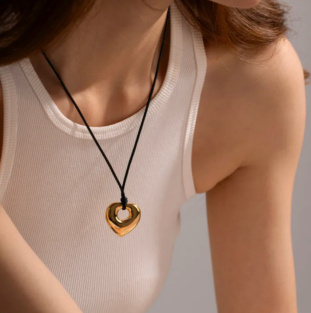 Un pendentif cœur moderne et massif, suspendu à un cordon noir sobre pour un effet saisissant. Un design inspiré des formes organiques, à la fois tendre et audacieux.

Matériau : Acier inoxydable couleur doré, finition miroir – cordon textile noir robuste – hypoallergénique.

Dimensions : Longueur totale : 61 cm – pendentif : 2,77 cm x 2,75 cm – poids : 7,06 g.

Design : Forme de cœur ouvert sculpté, effet bombé ultra lisse. Jeu de vide et de matière au centre pour un style contemporain et affirmé.

Style :