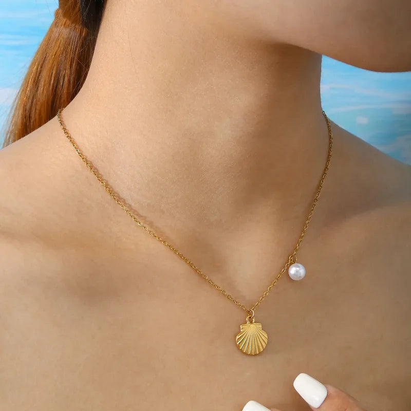 Collier en acier inoxydable doré pour femme, orné d’un pendentif coquillage et d’une perle blanche nacrée, inspiré de l’univers marin et estival, pour un style chic et naturel.