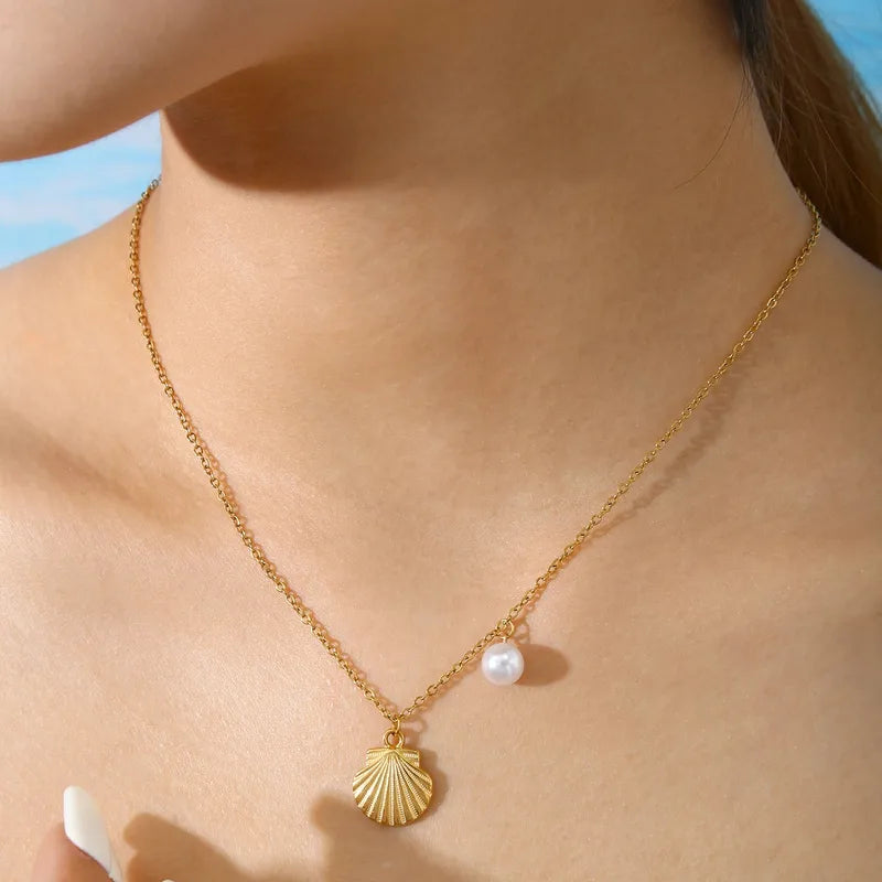 Collier en acier inoxydable doré pour femme, orné d’un pendentif coquillage et d’une perle blanche nacrée, inspiré de l’univers marin et estival, pour un style chic et naturel.