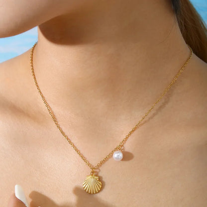 Collier en acier inoxydable doré pour femme, orné d’un pendentif coquillage et d’une perle blanche nacrée, inspiré de l’univers marin et estival, pour un style chic et naturel.