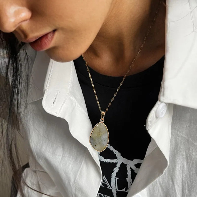 Collier couleur or en acier inoxydable avec pendentif ovale effet pierre naturelle grise.