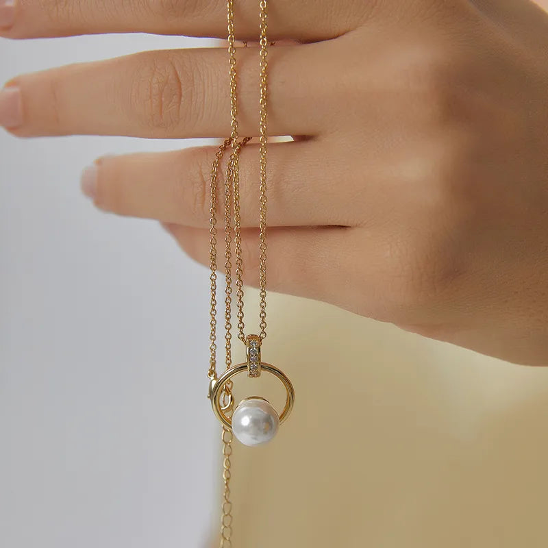 Collier doré pour femme avec pendentif cercle et perle blanche nacrée, orné de zircons scintillants sur la bélière. Bijou raffiné en plaqué or, au design harmonieux et féminin, idéal pour une tenue élégante ou une cérémonie