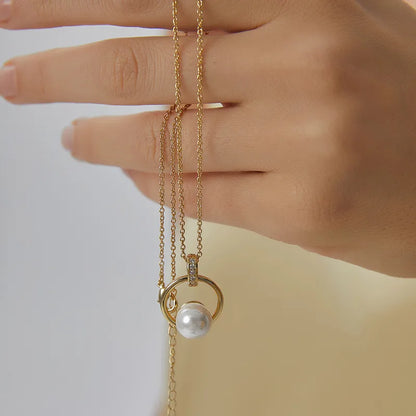 Collier doré pour femme avec pendentif cercle et perle blanche nacrée, orné de zircons scintillants sur la bélière. Bijou raffiné en plaqué or, au design harmonieux et féminin, idéal pour une tenue élégante ou une cérémonie