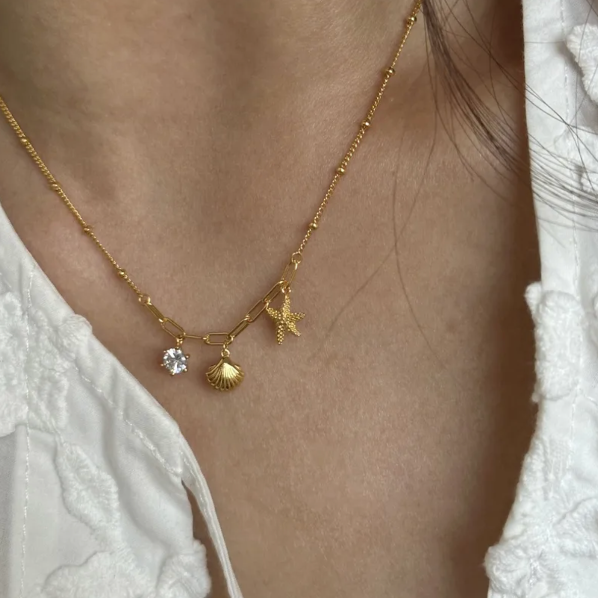 Ce collier doré revisite le thème marin avec élégance. Une chaîne mixte associe maillons larges et perles fines, rehaussée de trois pendentifs évocateurs : une coquille, une étoile de mer et une pierre claire scintillante. Un bijou en acier inoxydable conçu pour résister au temps, tout en évoquant les vacances.

Matériaux : Acier inoxydable, finition couleur or
Dimensions : 40 + 5 cm – poids : 3,5 g
Style : Marin, estival, symbolique