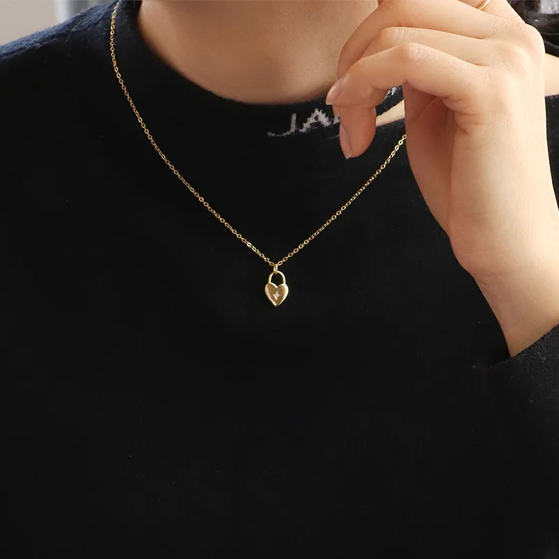 Ce collier doré à pendentif cœur évoque un amour précieux et protégé. La forme du cadenas en cœur, douce et symbolique, est rehaussée d’un petit zircon central étincelant, serti dans une étoile à huit branches gravée avec finesse. Un design épuré, où chaque détail exprime la force d’un lien intime.

Le rendu doré brillant de la chaîne et du pendentif évoque à la fois la chaleur et l’élégance intemporelle, pour un bijou à porter comme un talisman de cœur.