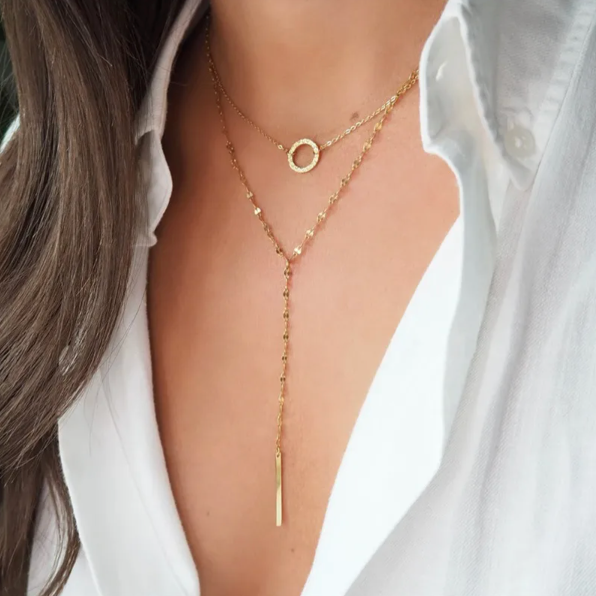 Un collier double rang à la silhouette élancée et épurée, qui joue sur les lignes graphiques et les volumes délicats. Le médaillon circulaire et la barre verticale s’équilibrent avec élégance pour une allure minimaliste et sophistiquée.

Matériau : Acier inoxydable couleur doré, finition brillante, résistant à l’eau, hypoallergénique.

Dimensions : Longueur totale env. 45 cm + extension – pendentif barre env. 5 cm de chute verticale. Léger et confortable au porté.

Design : Deux chaînes fines superposées : 