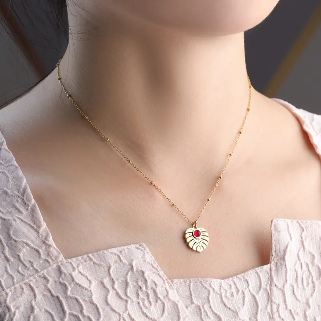 collier femme en acier inoxydable doré avec pendentif feuille Monstera orné d’une pierre rouge centrale, longueur 40 +5 cm, bijou végétal lumineux au style nature chic et estival