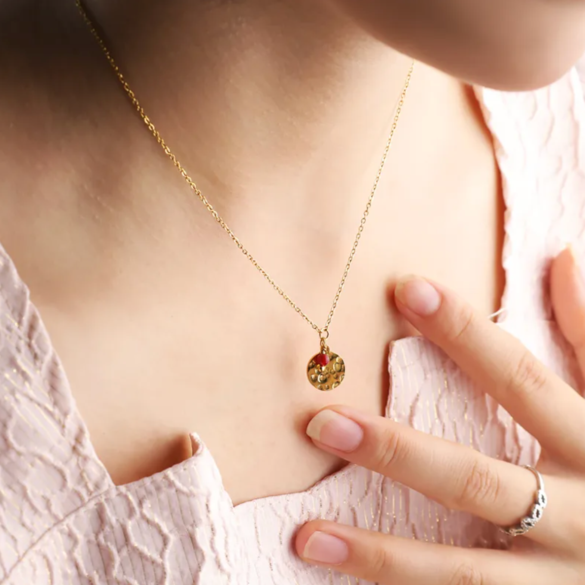 Collier doré pour femme avec médaillon rond martelé façon lune et petite pierre rouge type grenat. Bijou raffiné en acier inoxydable, résistant à l’eau et hypoallergénique, au design poétique et minimaliste