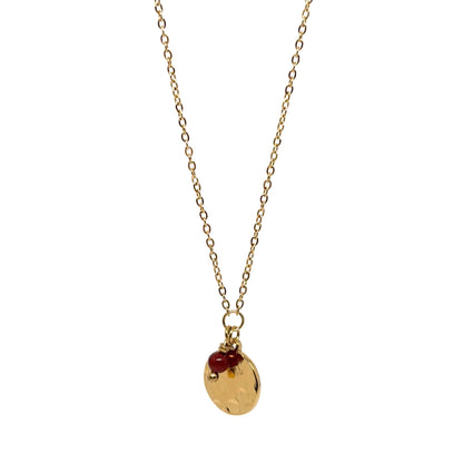 Collier doré pour femme avec médaillon rond martelé façon lune et petite pierre rouge type grenat. Bijou raffiné en acier inoxydable, résistant à l’eau et hypoallergénique, au design poétique et minimaliste