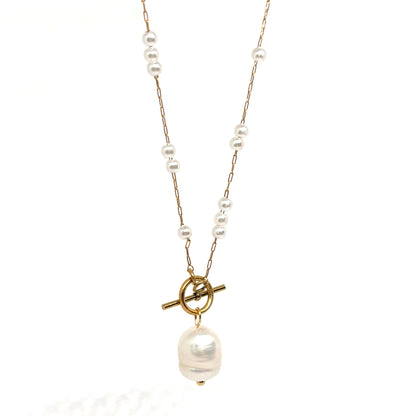 Collier doré pour femme en acier inoxydable, orné de perles blanches et d’un pendentif perle baroque suspendu à un fermoir toggle décoratif. Bijou raffiné, résistant à l’eau, au style chic et romantique idéal pour une tenue élégante ou bohème