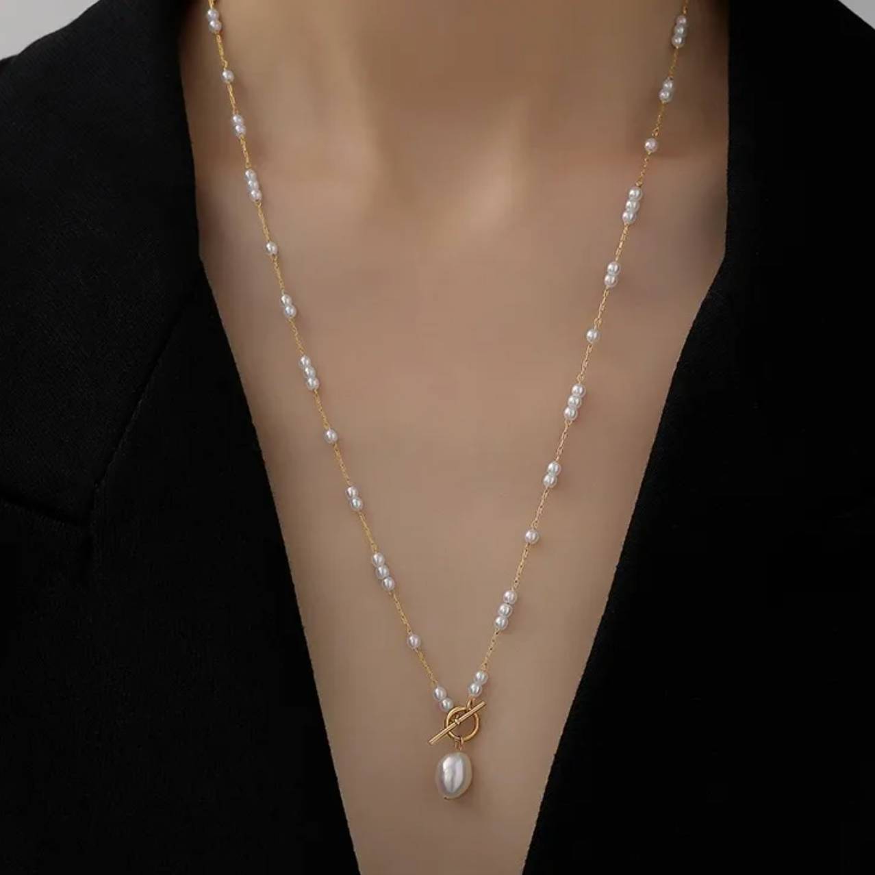 Collier doré pour femme en acier inoxydable, orné de perles blanches et d’un pendentif perle baroque suspendu à un fermoir toggle décoratif. Bijou raffiné, résistant à l’eau, au style chic et romantique idéal pour une tenue élégante ou bohème