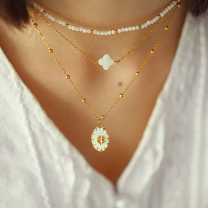 Collier double chaîne pour femme en acier inoxydable couleur doré, orné d’un médaillon en nacre naturelle avec étoile dorée à huit branches. Bijou lumineux et raffiné, résistant à l’eau et hypoallergénique, au style céleste et élégant