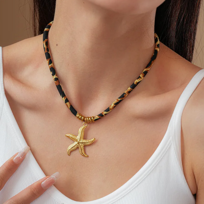 Collier pour femme avec pendentif étoile de mer couleur doré suspendu à un cordon à motif léopard. Bijou original en acier titane, résistant à l’eau et hypoallergénique, alliant esprit marin et style bohème audacieux.