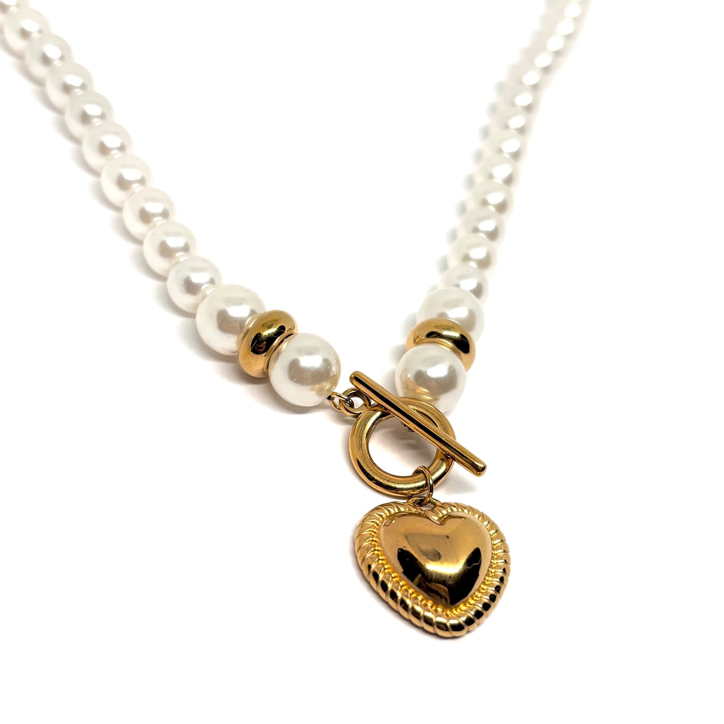 Collier pour femme composé de perles blanches nacrées et de perles dorées, orné d’un pendentif cœur bombé couleur or avec fermoir toggle à l’avant. Bijou romantique et vintage en acier inoxydable, résistant à l’eau et hypoallergénique.