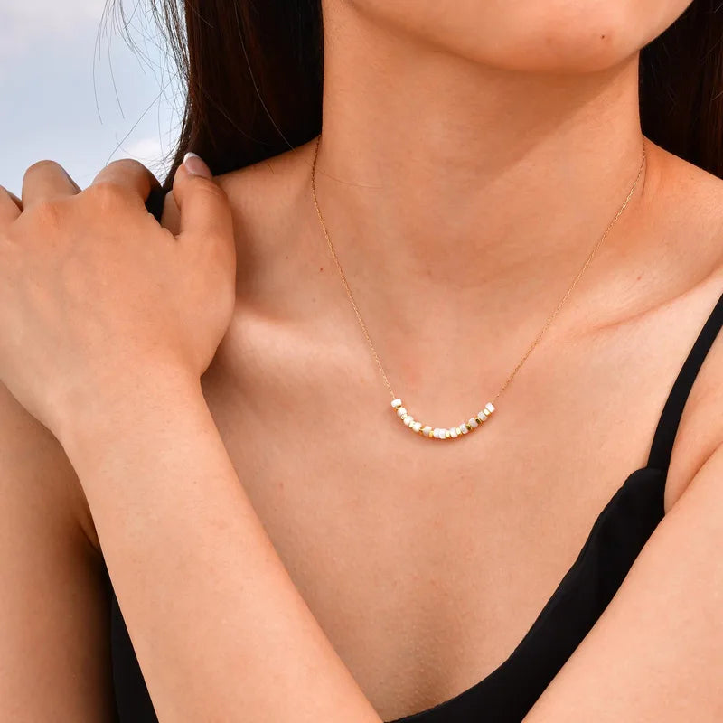 Ce collier minimaliste allie élégance intemporelle et style décontracté chic. Il se compose d’une fine chaîne couleur or ornée de perles plates blanches et dorées, disposées en alternance pour créer un rythme visuel doux et équilibré. Le contraste subtil entre la nacre blanche et le doré lumineux en fait un bijou délicat, parfait pour illuminer le décolleté avec discrétion.