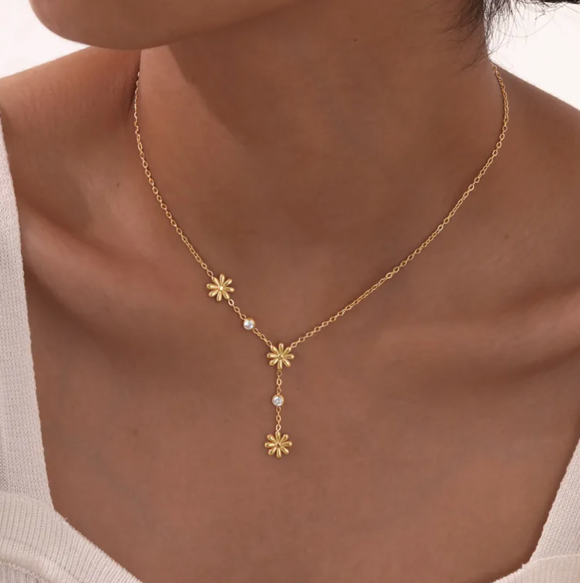 Un collier délicat et graphique, jouant sur une asymétrie florale et des cristaux étincelants. Parfait pour apporter une touche de lumière à un look sobre ou romantique.

Matériau : Acier inoxydable couleur doré, orné de cristaux transparents – résistant à l’eau, hypoallergénique.

Dimensions : Longueur ajustable 40 à 45 cm – pendentifs fleurs : 0,9 cm – poids léger : 4 g.

Design : Trois petites fleurs dorées disposées de façon décalée, reliées par une fine chaîne ponctuée de pierres brillantes. Un jeu de 