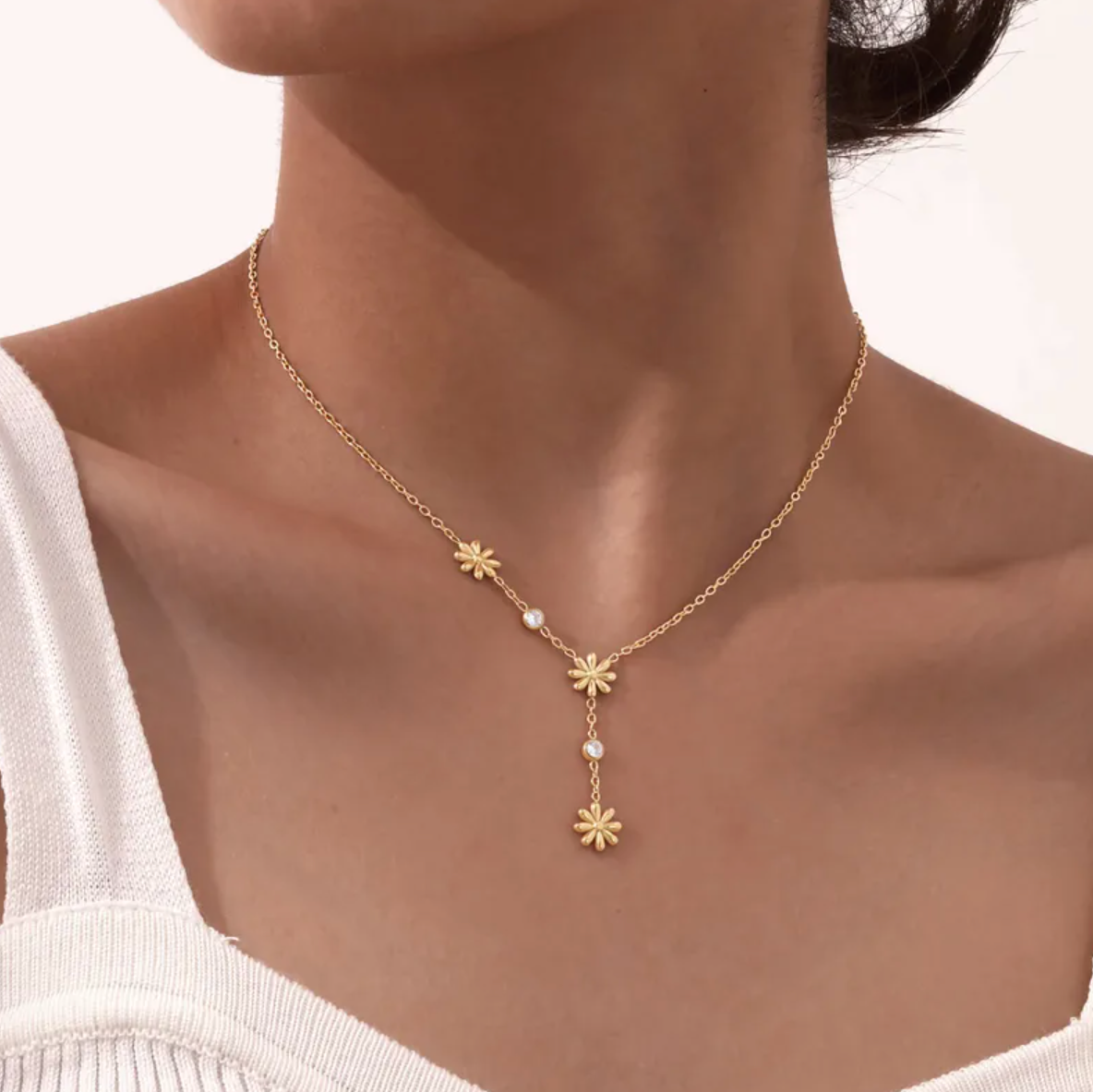 Un collier délicat et graphique, jouant sur une asymétrie florale et des cristaux étincelants. Parfait pour apporter une touche de lumière à un look sobre ou romantique.

Matériau : Acier inoxydable couleur doré, orné de cristaux transparents – résistant à l’eau, hypoallergénique.

Dimensions : Longueur ajustable 40 à 45 cm – pendentifs fleurs : 0,9 cm – poids léger : 4 g.

Design : Trois petites fleurs dorées disposées de façon décalée, reliées par une fine chaîne ponctuée de pierres brillantes. Un jeu de 