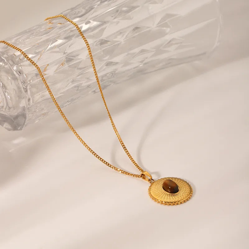 Ce collier médaille en acier inoxydable doré, serti d’un œil de tigre naturel, est un véritable talisman énergétique. Le motif texturé en rayons solaires renforce la puissance de cette pierre aux reflets ambrés, symbole de courage et de confiance en soi.

Matériau : Acier inoxydable doré, pierre naturelle œil de tigre, hypoallergénique, résistant à l’eau et à l’oxydation.