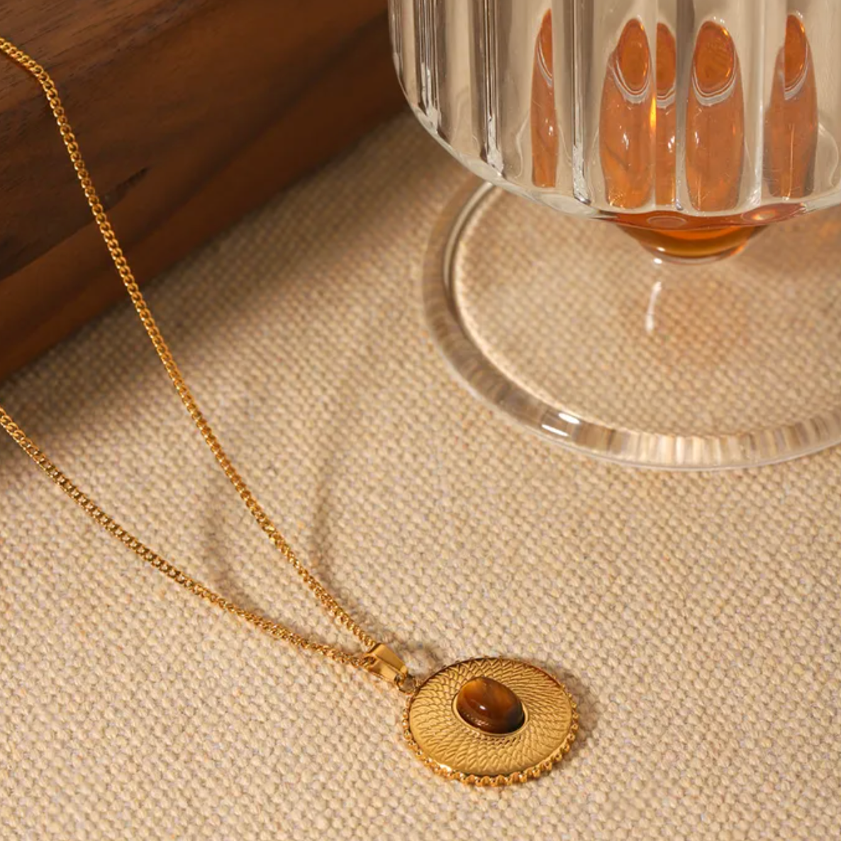 Ce collier médaille en acier inoxydable doré, serti d’un œil de tigre naturel, est un véritable talisman énergétique. Le motif texturé en rayons solaires renforce la puissance de cette pierre aux reflets ambrés, symbole de courage et de confiance en soi.