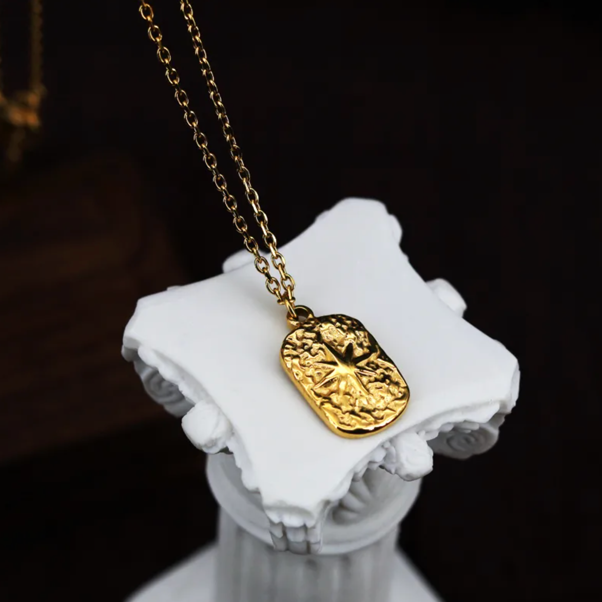 Évoquant une carte céleste ancienne, ce collier doré orné d'une médaille martelée met en valeur une étoile du Nord en relief, symbole de repère et de guidance. Le contraste entre les textures brutes et le poli du motif central donne une pièce forte, authentique et pleine de caractère.

Matériaux : Acier titane, finition couleur or
Dimensions : pendentif 1,5 cm x 1 cm – chaîne 40 + 5 cm
Style : Astrologique, médaillon vintage, symbolique