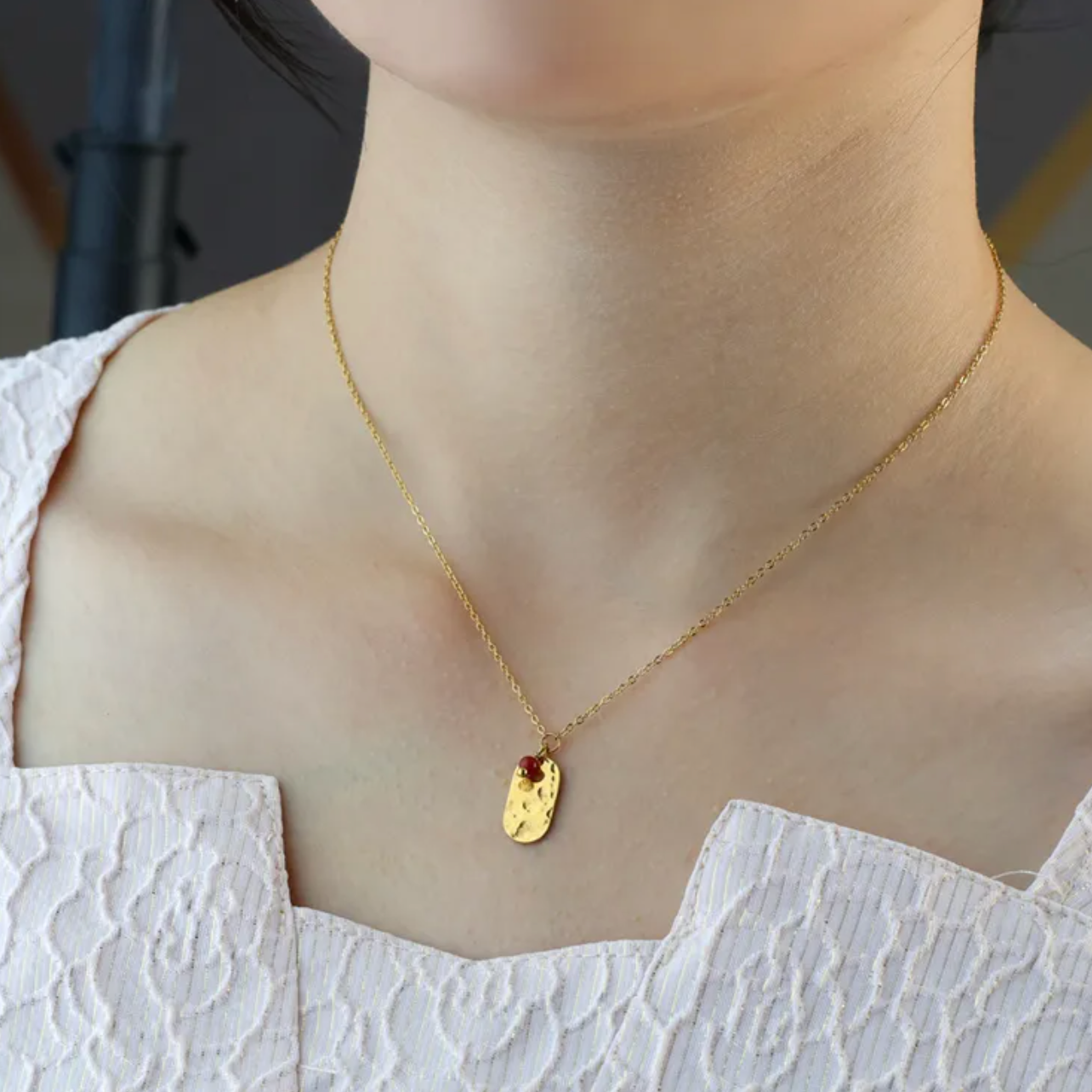 Ce collier doré révèle un pendentif rectangulaire martelé orné d’une perle rouge cerise. Une pièce simple mais pleine de caractère.

Matériaux : Acier inoxydable doré – résistant à l’eau, hypoallergénique, finition martelée pour un effet texturé chic.

Dimensions : Longueur 40 + 5 cm – pendentif 15 mm x 8 mm – poids ≈ 2,5 g.

Style : Minimaliste et moderne, ce bijou apporte une touche de chaleur et d’originalité. Idéal pour un look quotidien ou un cadeau raffiné.