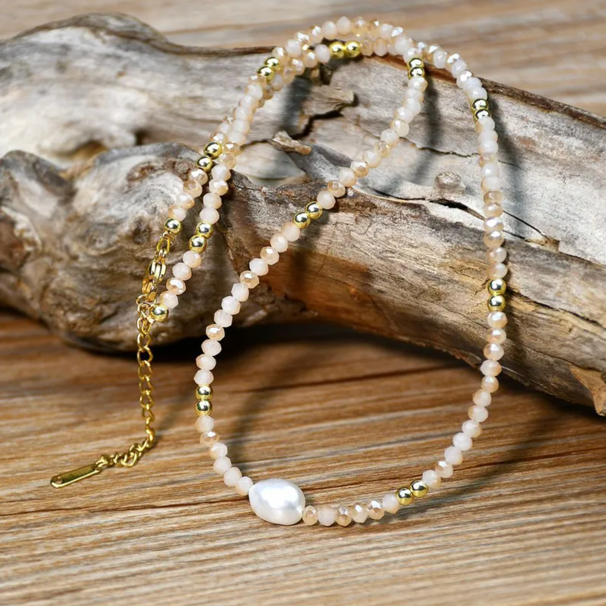 Un collier fin et délicat, composé de perles beige nude, de cristaux dorés, et d’une perle blanche d’eau douce centrale. L’association parfaite entre légèreté, douceur et sophistication discrète.

Matériau : Acier inoxydable couleur doré (316L), cristal, perles synthétiques + perle d’eau douce centrale, hypoallergénique, résistant à l’eau et à l’oxydation.

Dimensions : Longueur 40 cm + 5 cm de rallonge – fermoir mousqueton doré sécurisé.

Design : Enfilade de perles facettées beige rosé, rythmée par de min