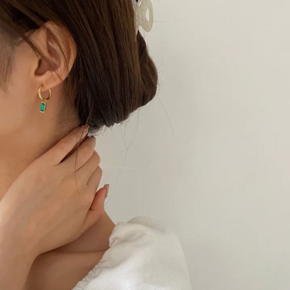 Boucles d’oreilles créoles dorées en acier inoxydable avec pendentif rectangulaire serti d’un cristal vert émeraude. Bijou chic et minimaliste, résistant à l’eau et hypoallergénique, pour un éclat discret et raffiné